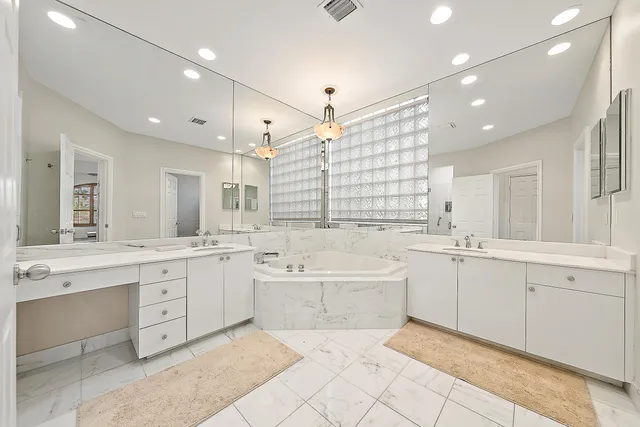 a large white bathroom with a large tub sink vanity granite and a large mirror