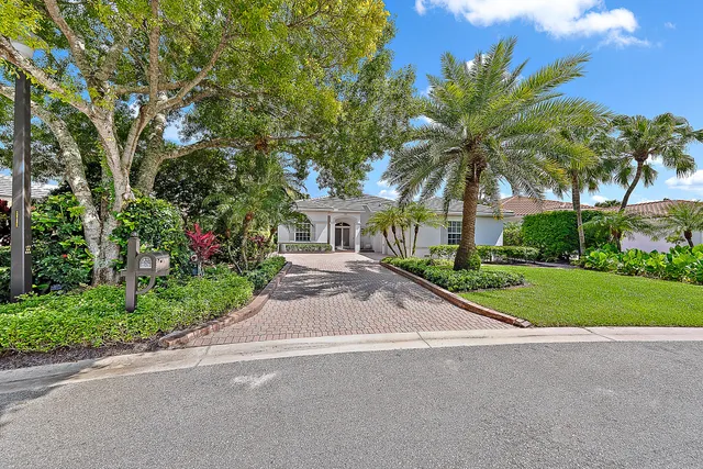 a front view of house with small garden and palm trees
