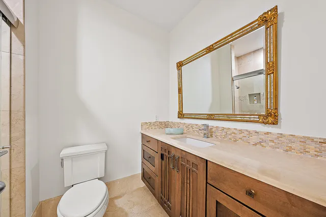 a bathroom with a granite countertop sink toilet and mirror