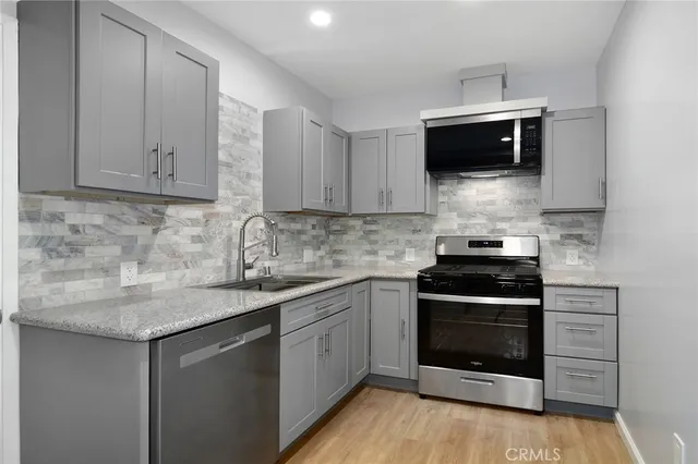 a kitchen with stainless steel appliances granite countertop a stove top oven microwave and sink