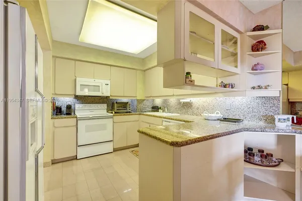 a kitchen with granite countertop a sink a stove and cabinets