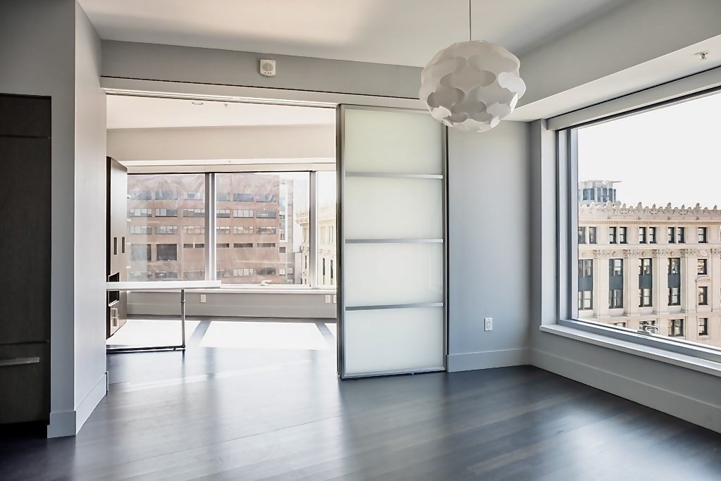 110 Stuart Street, Unit 16H Boston, MA 02116 - Photo 3 of 17 a view of an empty room with wooden floor and a window