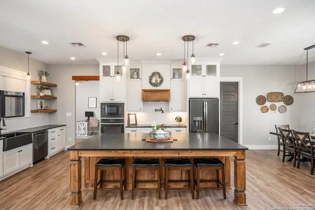 a open kitchen with stainless steel appliances granite countertop a stove refrigerator and a wooden cabinets with wooden floor