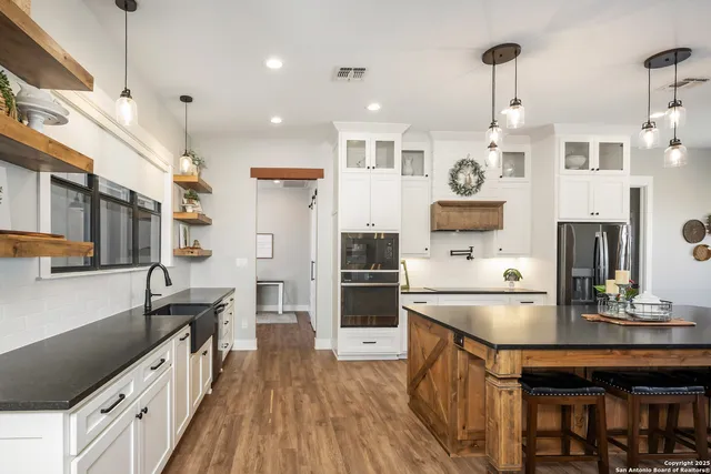 a kitchen with stainless steel appliances granite countertop a sink a stove and a refrigerator