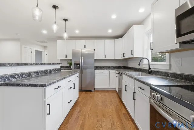 a large kitchen with granite countertop a sink a counter top space stainless steel appliances and cabinets