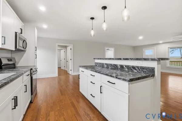 a large kitchen with stainless steel appliances granite countertop a lot of counter space and wooden floor