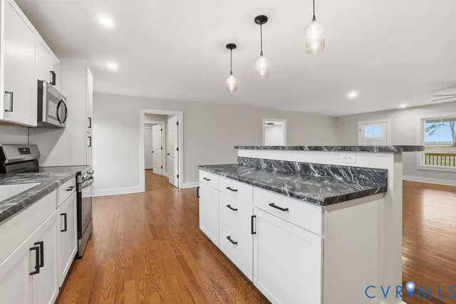 a large kitchen with stainless steel appliances granite countertop a lot of counter space and wooden floor