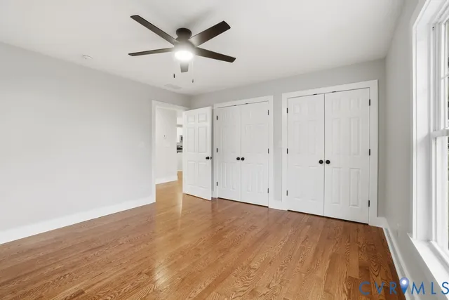 an empty room with wooden floor and ceiling fan
