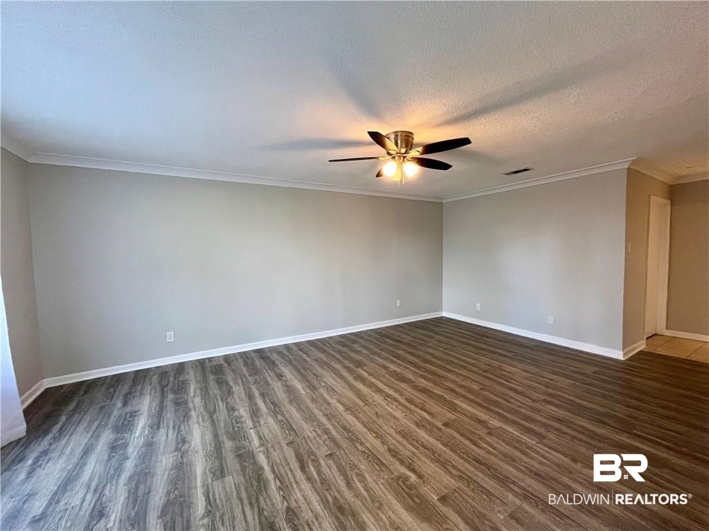 8636 Boe Road Irvington, AL 36544 - Photo 8 of 22 Spare room with dark wood-type flooring, crown molding, a textured ceiling, and a ceiling fan