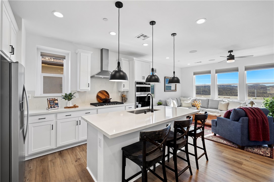821 Cornelia Way Rancho Mission Viejo, CA 92694 - Photo 3 of 61 a kitchen with stainless steel appliances granite countertop a stove a sink dishwasher a dining table and chairs with wooden floor