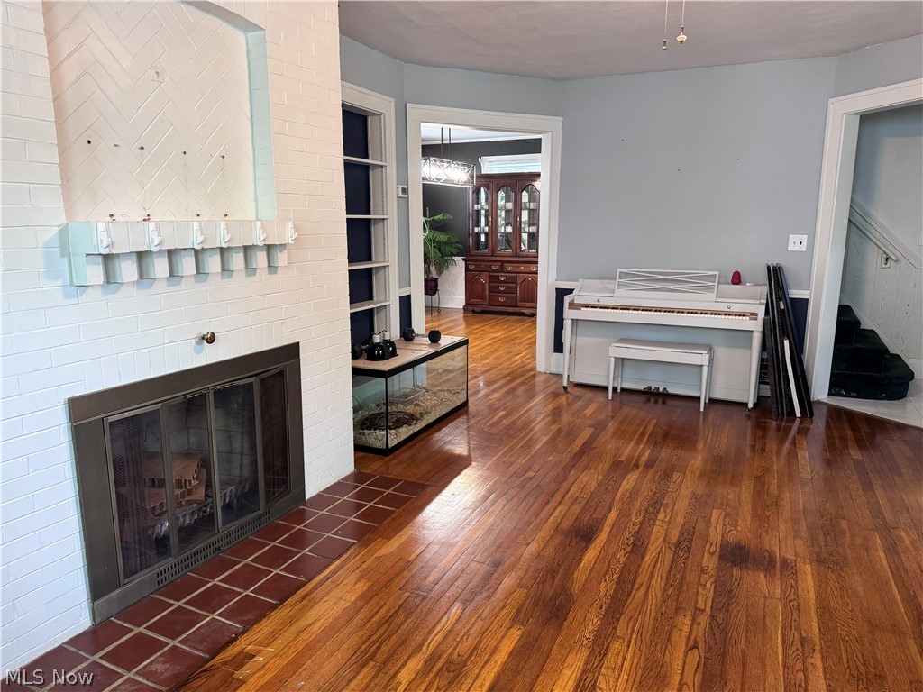 7121 North Lima Road Youngstown, OH 44514 - Photo 11 of 37 Living area featuring wood flooring, a fireplace with a tiled hearth, a white brick surround, and built-in shelving