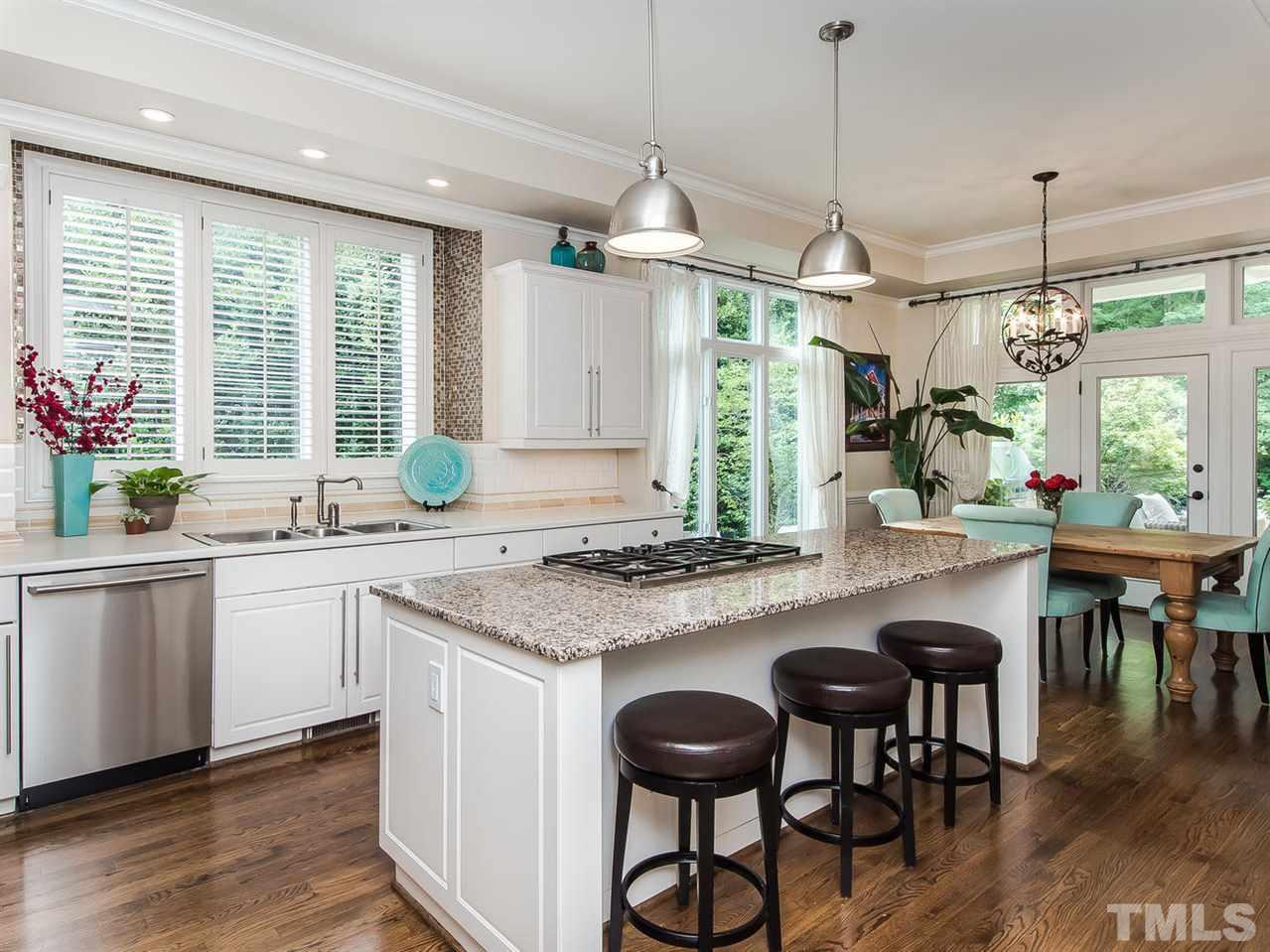 509 Lake Boone Trail Raleigh, NC 27608 - Photo 6 of 25 a kitchen with kitchen island granite countertop a table chairs sink and wooden floor