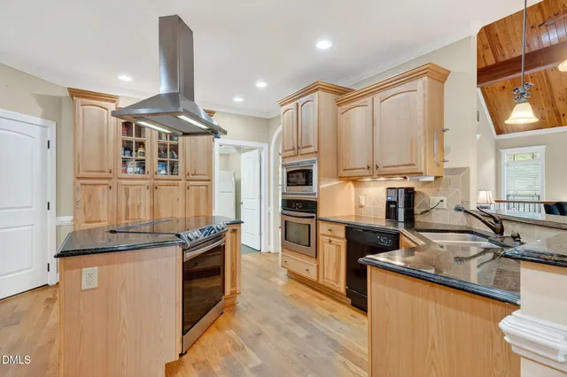 a kitchen with stainless steel appliances granite countertop a sink a stove top oven a dining table and chairs with wooden floor