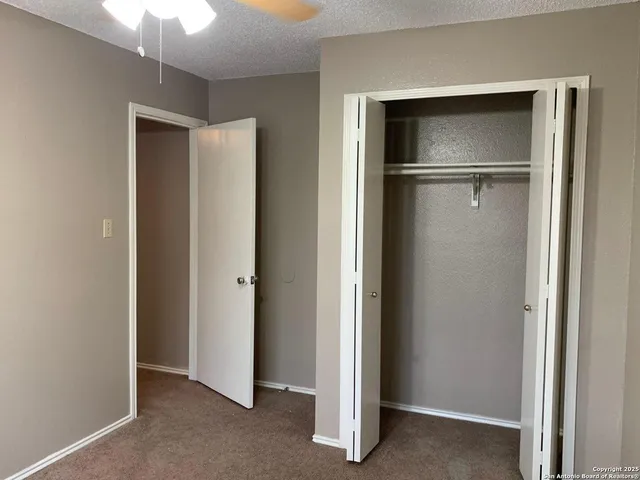 a view of an empty room with a fireplace and a chandelier fan