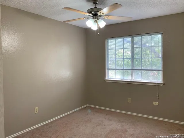 an empty room with a window and a fan