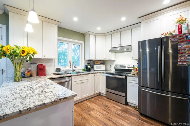 a kitchen with a sink dishwasher a stove and white cabinets with wooden floor