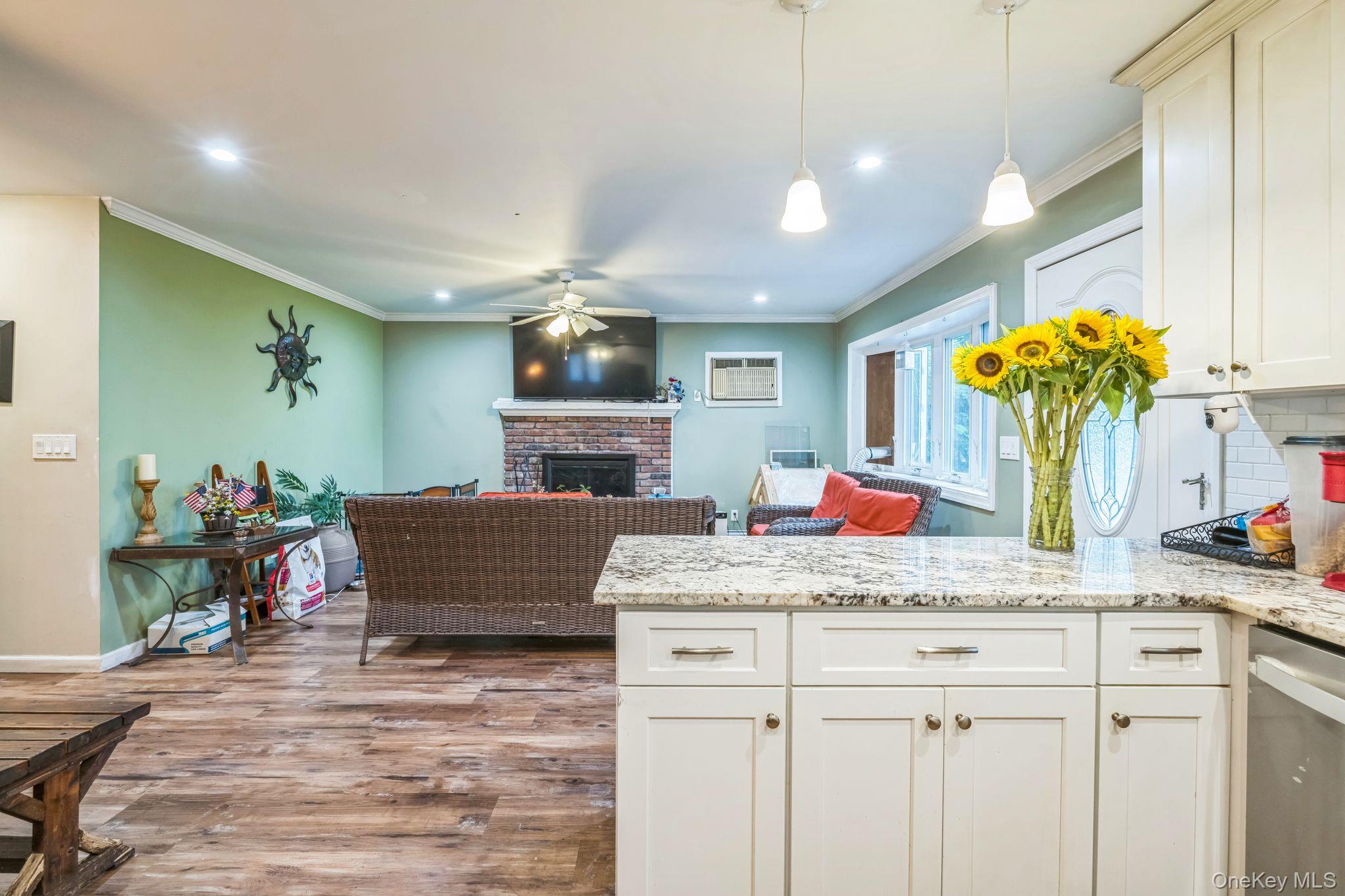 39 Willow Road Rocky Point, NY 11778 - Photo 12 of 18 Kitchen featuring a peninsula, a fireplace, wood finished floors, ornamental molding, and stainless steel dishwasher