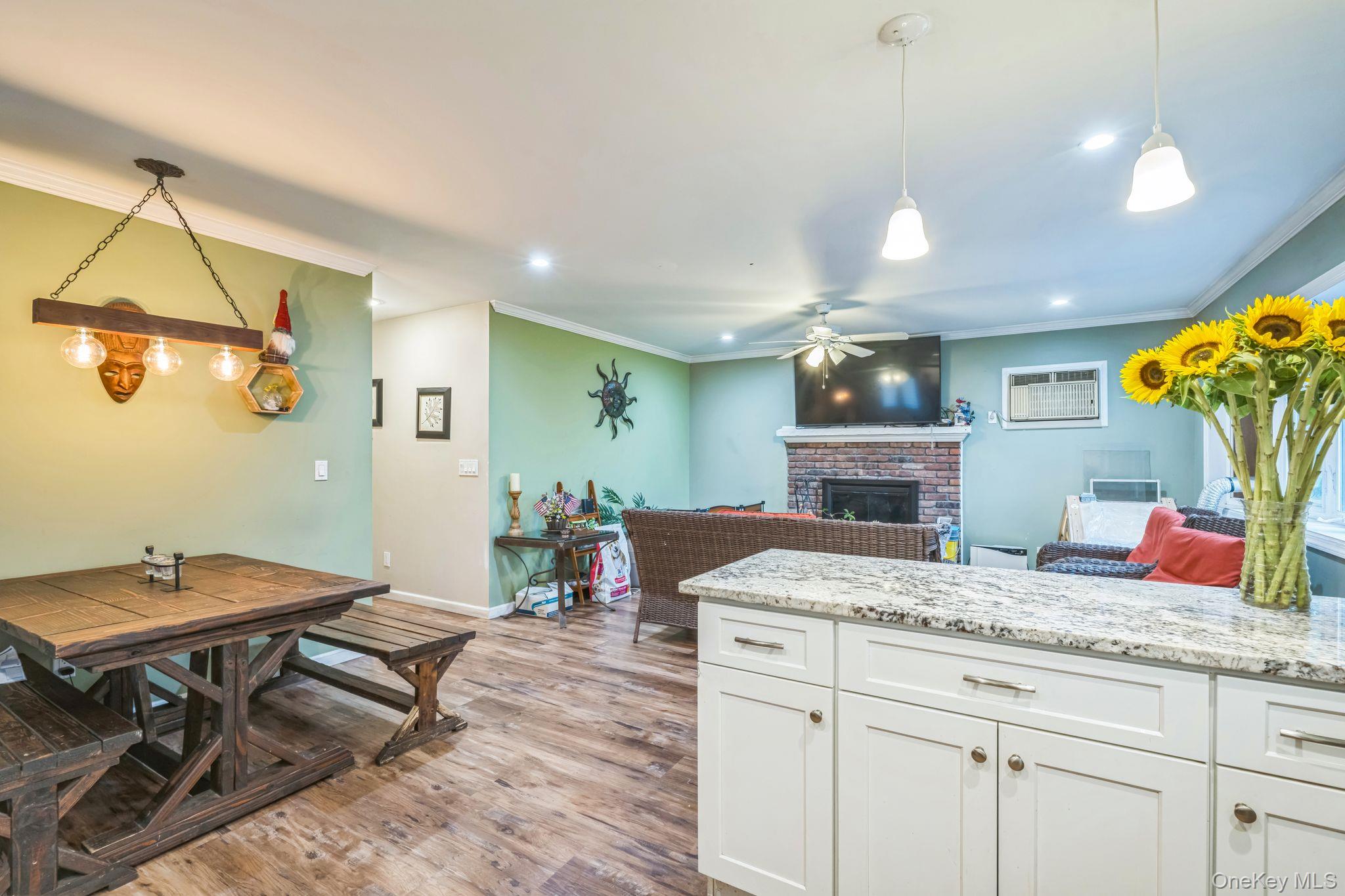 39 Willow Road Rocky Point, NY 11778 - Photo 18 of 18 Kitchen featuring ornamental molding, light wood finished floors, a brick fireplace, white cabinets, and open floor plan