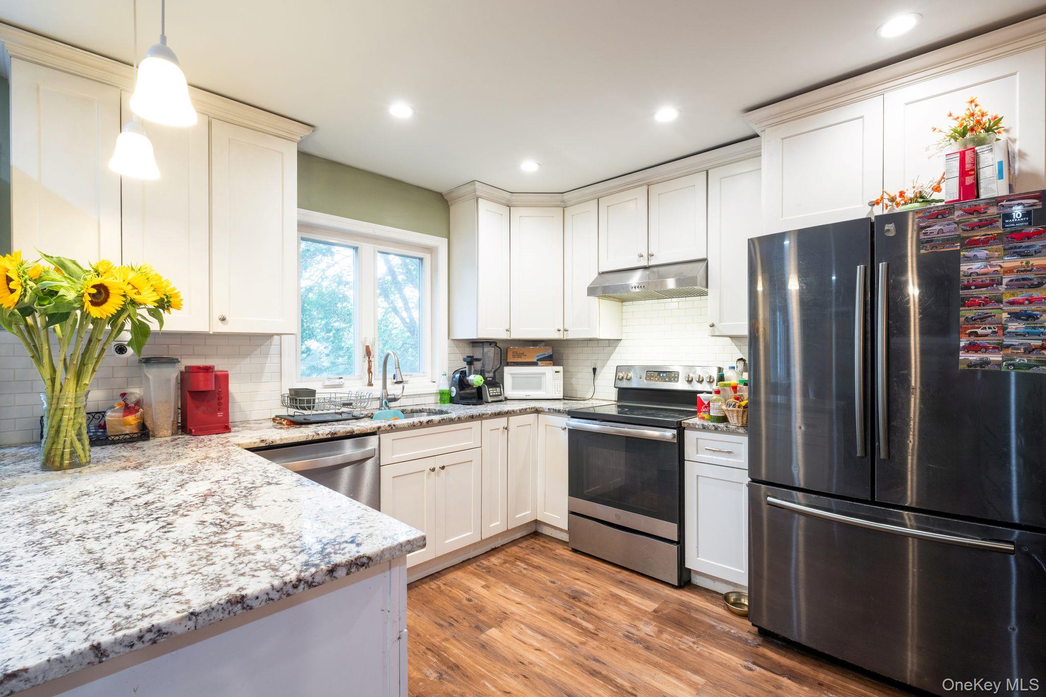 39 Willow Road Rocky Point, NY 11778 - Photo 7 of 18 Kitchen with appliances with stainless steel finishes, light wood-style floors, light stone counters, recessed lighting, and pendant lighting