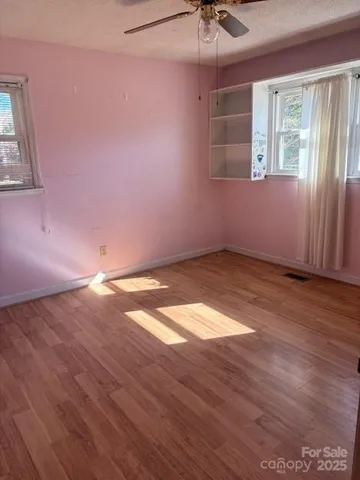 an empty room with windows and fan
