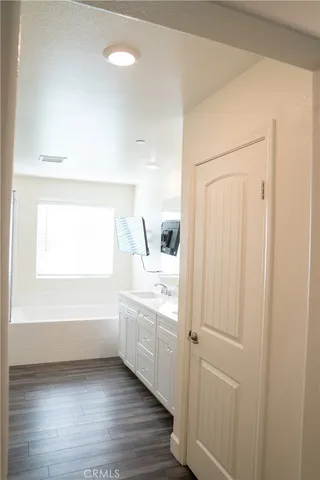 an empty room with wooden floor cabinet and windows