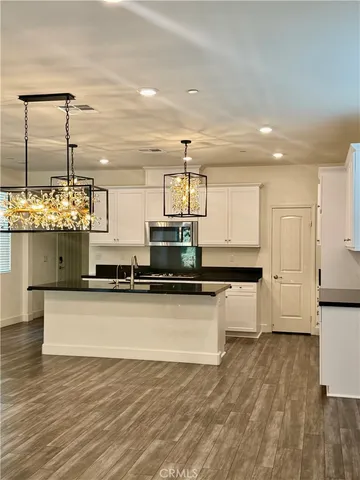 a kitchen with kitchen island granite countertop a stove and a wooden floors