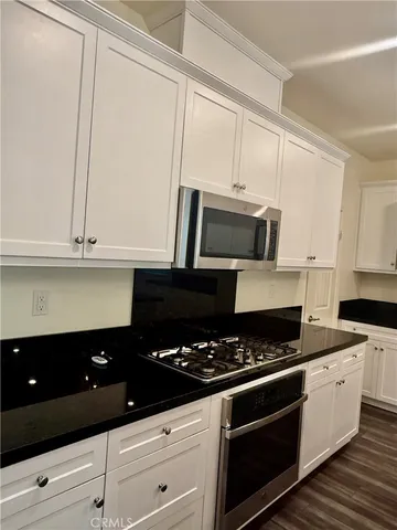 a kitchen with stainless steel appliances granite countertop a stove a sink and a microwave