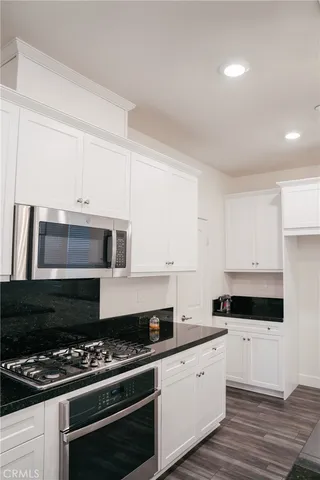 a kitchen with granite countertop a stove and white cabinets