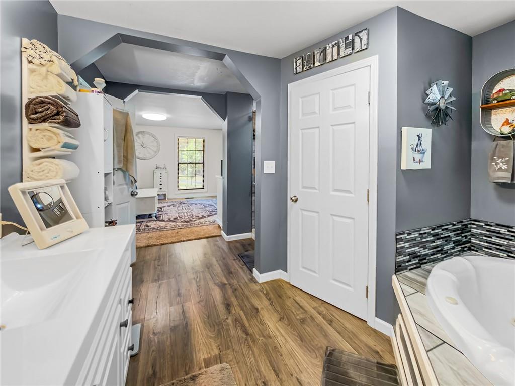 1024 Trail Street Valley, AL 36854 - Photo 16 of 37 Primary Bathroom Suite Featuring Dual Vanities with White Cabinetry, Wood-Finish Flooring, and Decorative Tile Accents