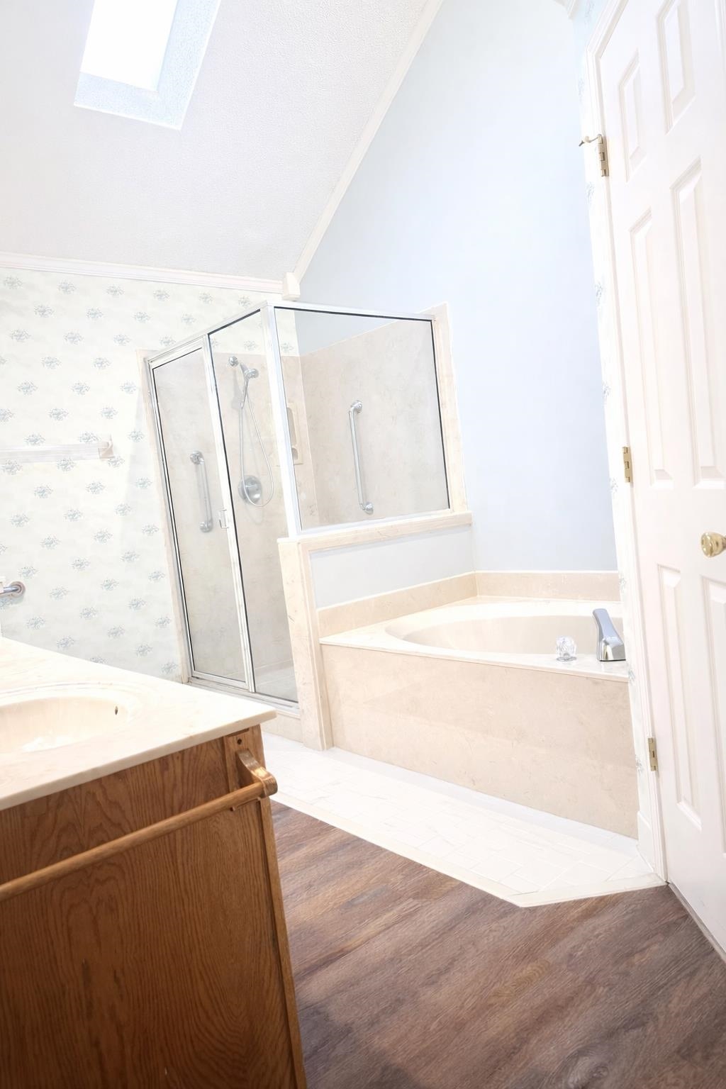 6708 Dawnhill Road Bartlett, TN 38135 - Photo 14 of 18 Alcove soaking tub with light-toned surround, glass-enclosed shower with grab bars, and wood-finish flooring