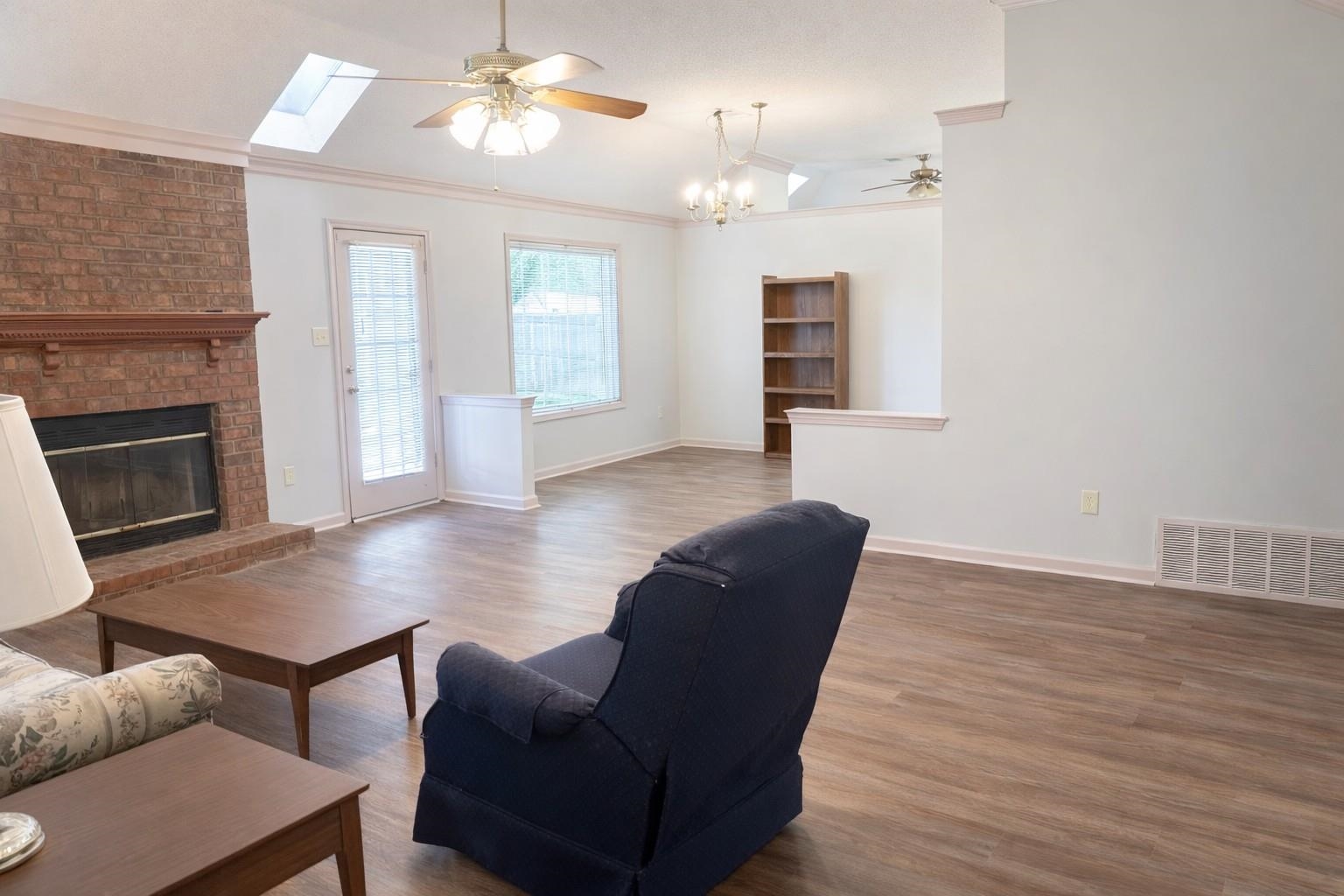 6708 Dawnhill Road Bartlett, TN 38135 - Photo 5 of 18 Spacious living area featuring vaulted ceilings, wood-finish flooring, a brick fireplace with a wood mantle, and skylights