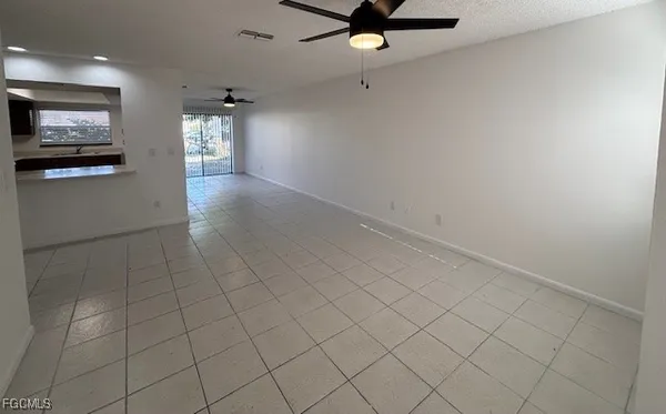 an empty room with windows and ceiling fan