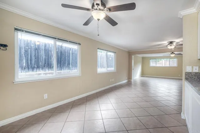 a view of an empty room with window and chandelier fan