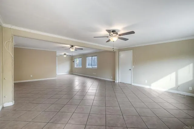 a view of an empty room with chandelier fan and fire place