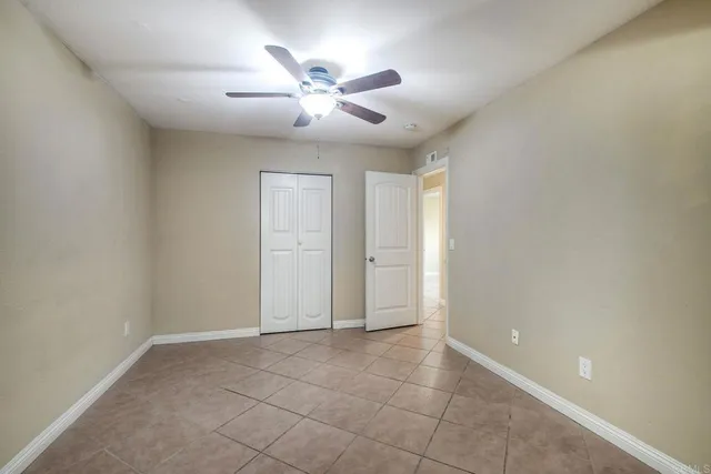 an empty room with chandelier fan and windows