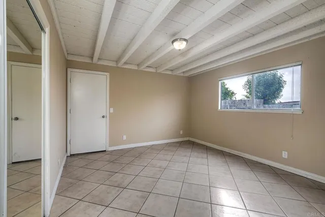 a view of an empty room with window and chandelier fan