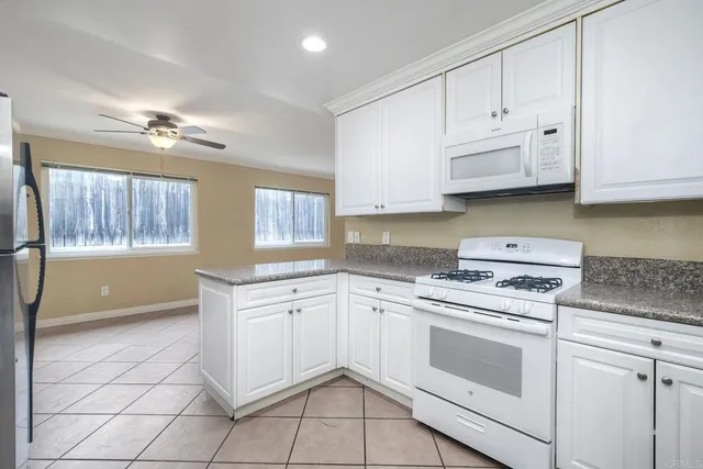 a kitchen with granite countertop white cabinets and white appliances
