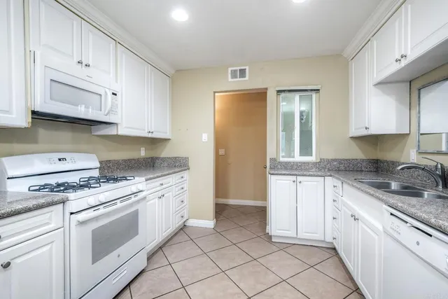 a kitchen with granite countertop white cabinets and white appliances