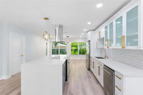 a large kitchen with kitchen island a large window a sink and a stove