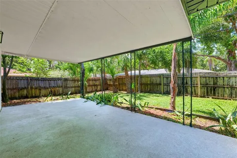 a backyard of a house with plants and large tree