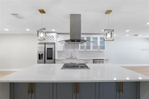 a view of a kitchen with kitchen island stainless steel appliances a sink and living room view