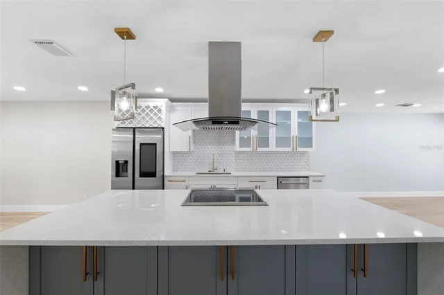 a view of a kitchen with kitchen island stainless steel appliances a sink and living room view