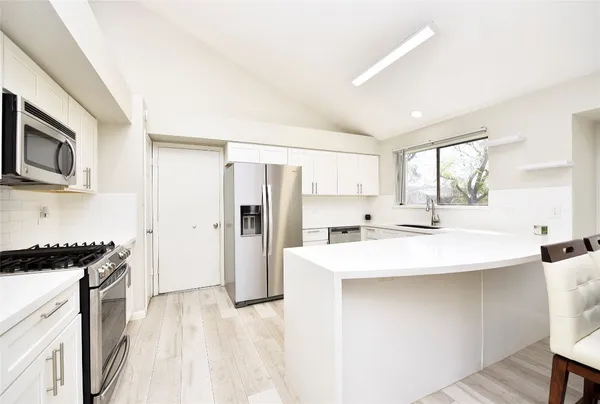 a kitchen with stainless steel appliances a sink a stove a refrigerator and cabinets