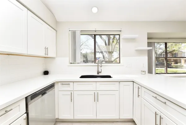 a kitchen with white cabinets and a window