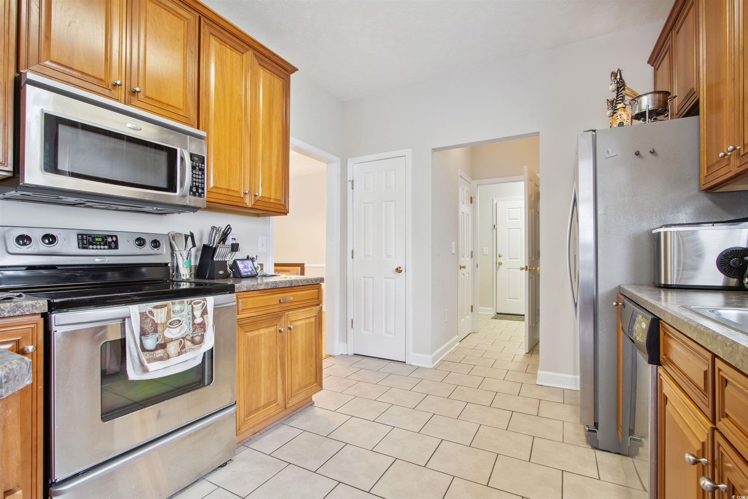 Undisclosed Address Conway, SC 29526 - Photo 8 of 26 Kitchen featuring appliances with stainless steel finishes, brown cabinetry, and light tile patterned floors