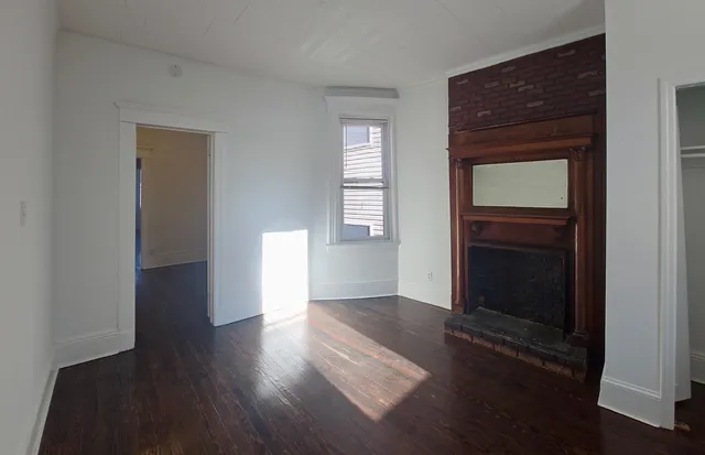 an empty room with wooden floor closet and windows