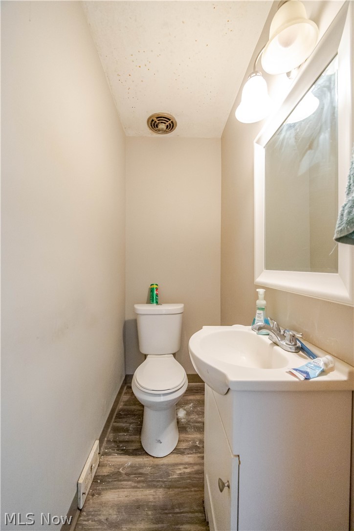 3825 Mayfield Road Cleveland Heights, OH 44121 - Photo 9 of 27 Bathroom featuring a vanity with a white ceramic sink, a wall-mounted mirror, and wood-finish flooring