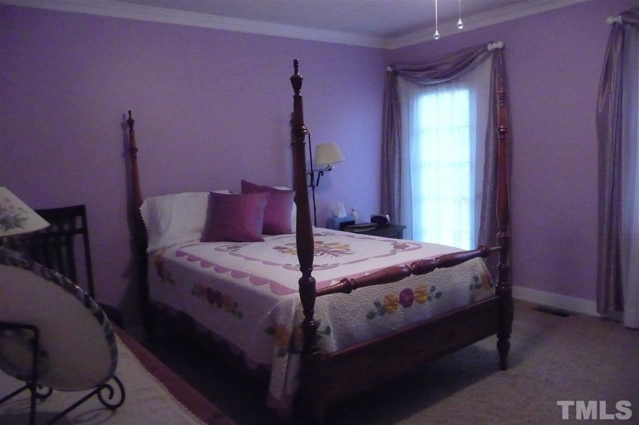 8705 Brandon Station Road Raleigh, NC 27613 - Photo 8 of 16 a bed sitting in a bedroom next to a window