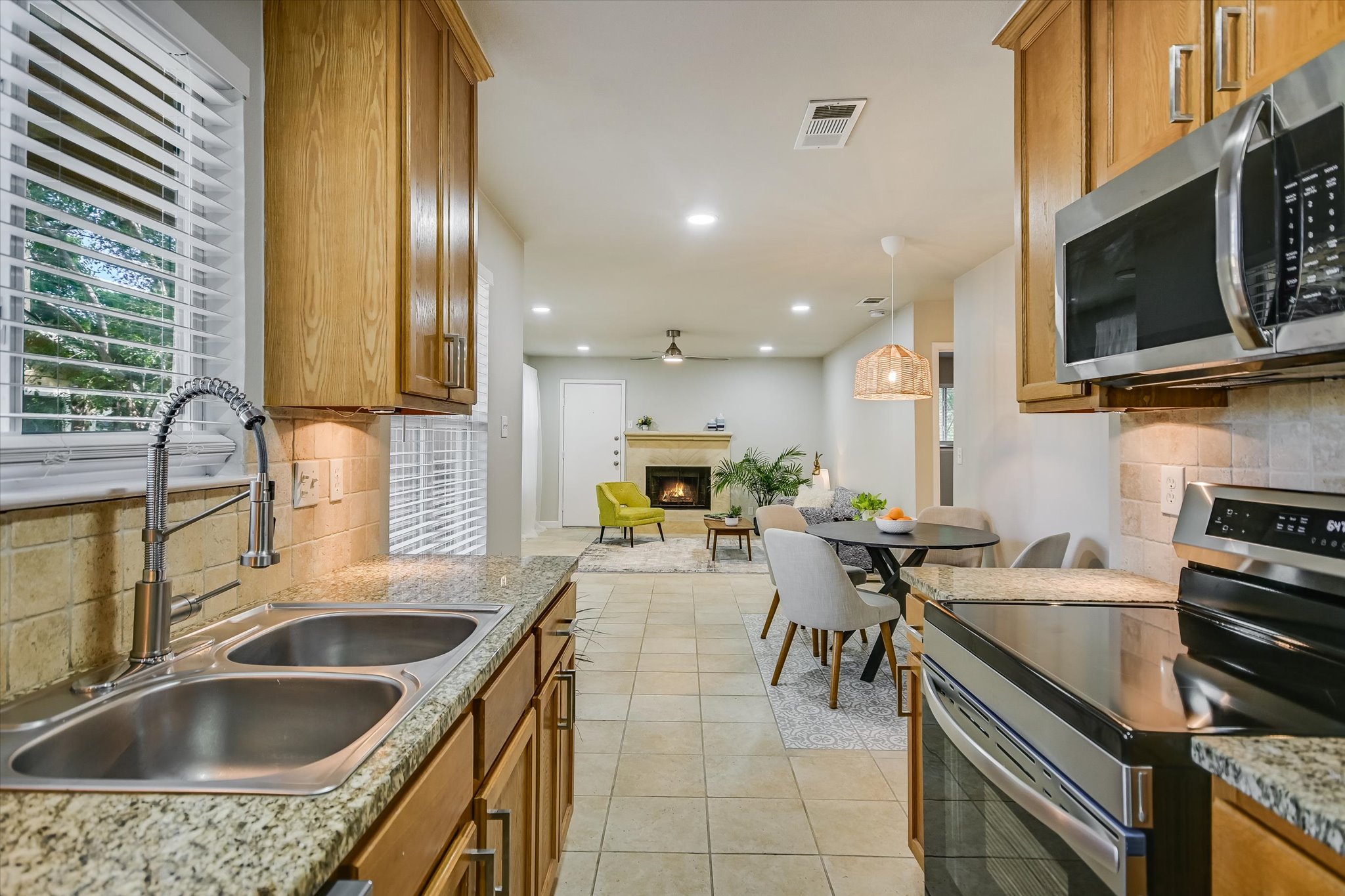 4902 Duval Road, Unit H1 Austin, TX 78727 - Photo 8 of 20 A well-appointed kitchen offers granite counters and stainless steel appliances, flowing seamlessly into a cozy living area with a warming fireplace.