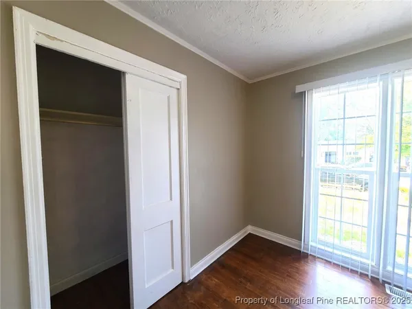 an empty room with wooden floor closet and windows
